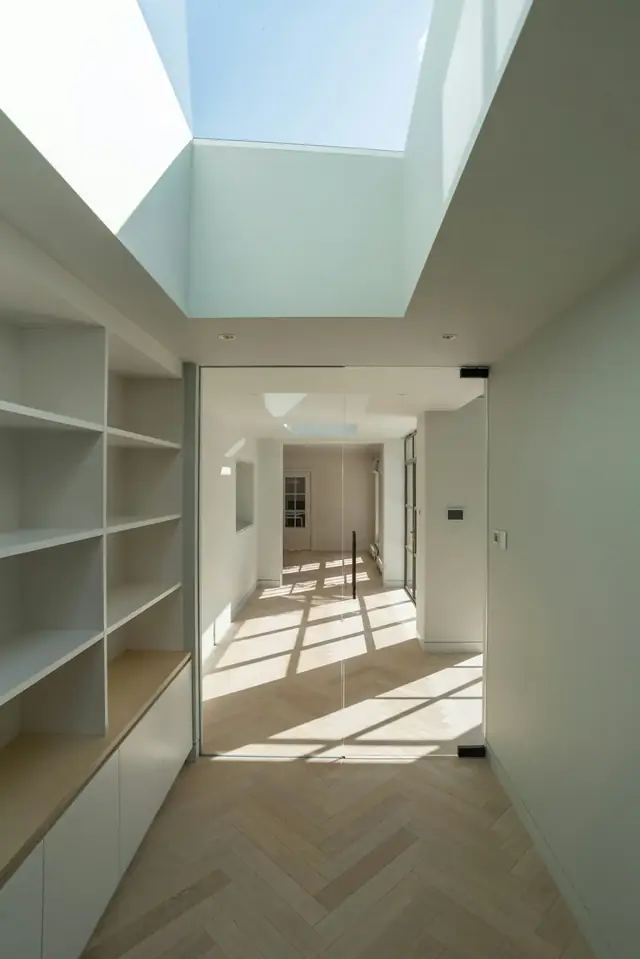Couloir rénové et lumineux avec étagères intégrées et parquet en chevrons