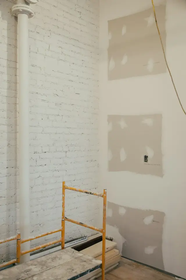 Mur intérieur en cours de finition : plaques de plâtre enduites et petit escabeau