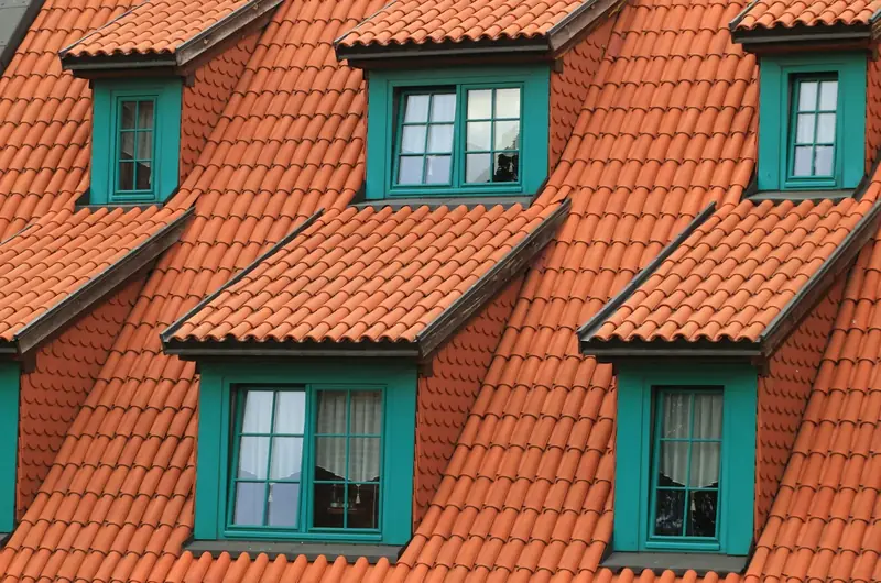 Toit de tuiles orangées percé de lucarnes aux menuiseries vertes, vu de près